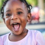 Picture of young African American girl smiling. Join flight to help homeless children