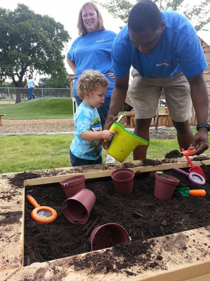 photo of two teachers with little child playing in the sand box