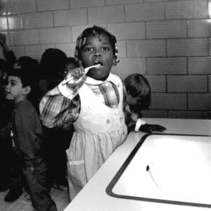 black and white photo of black student brushing her teeth almost 35 years ago