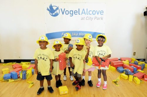 Kids playing with toy bricks in hard hats Groundbreaking